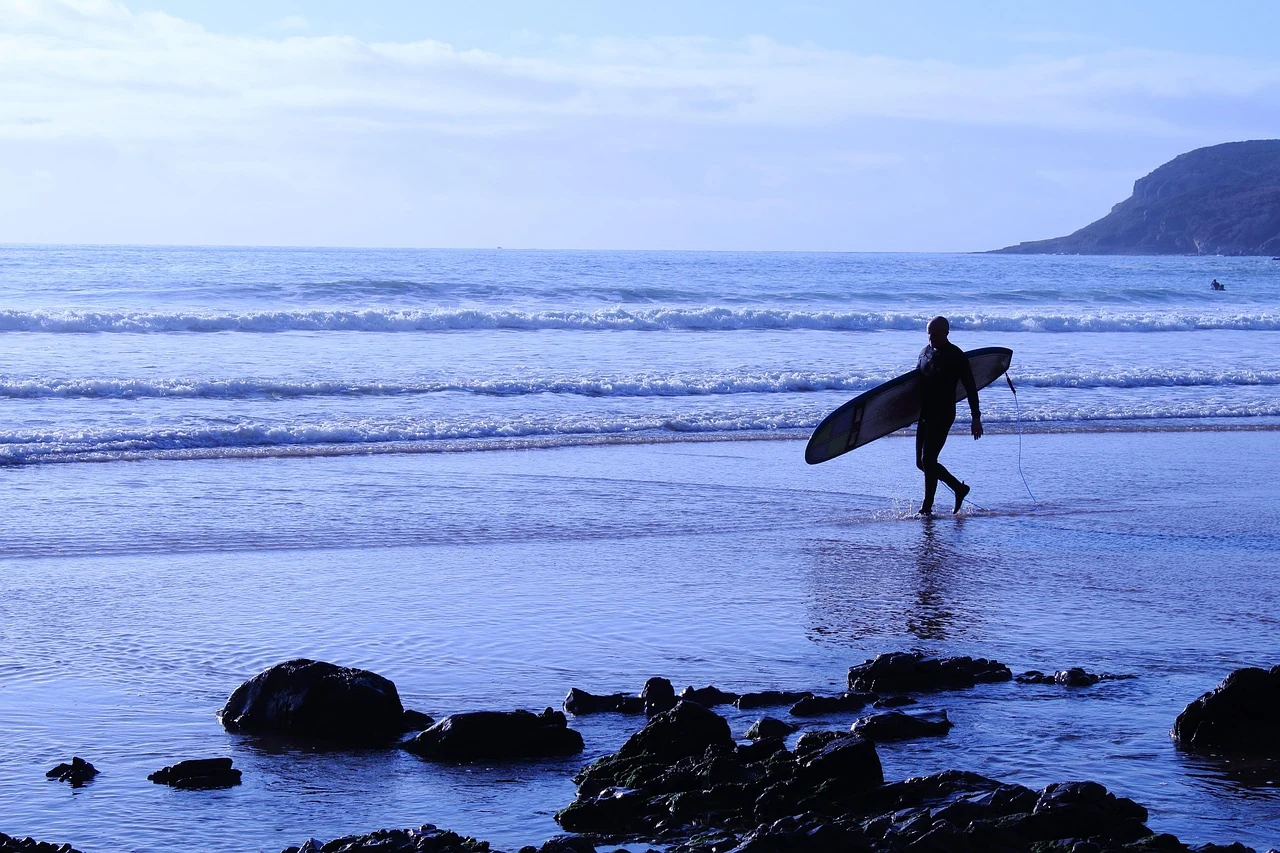 A surfer carrying a board at the shoreline